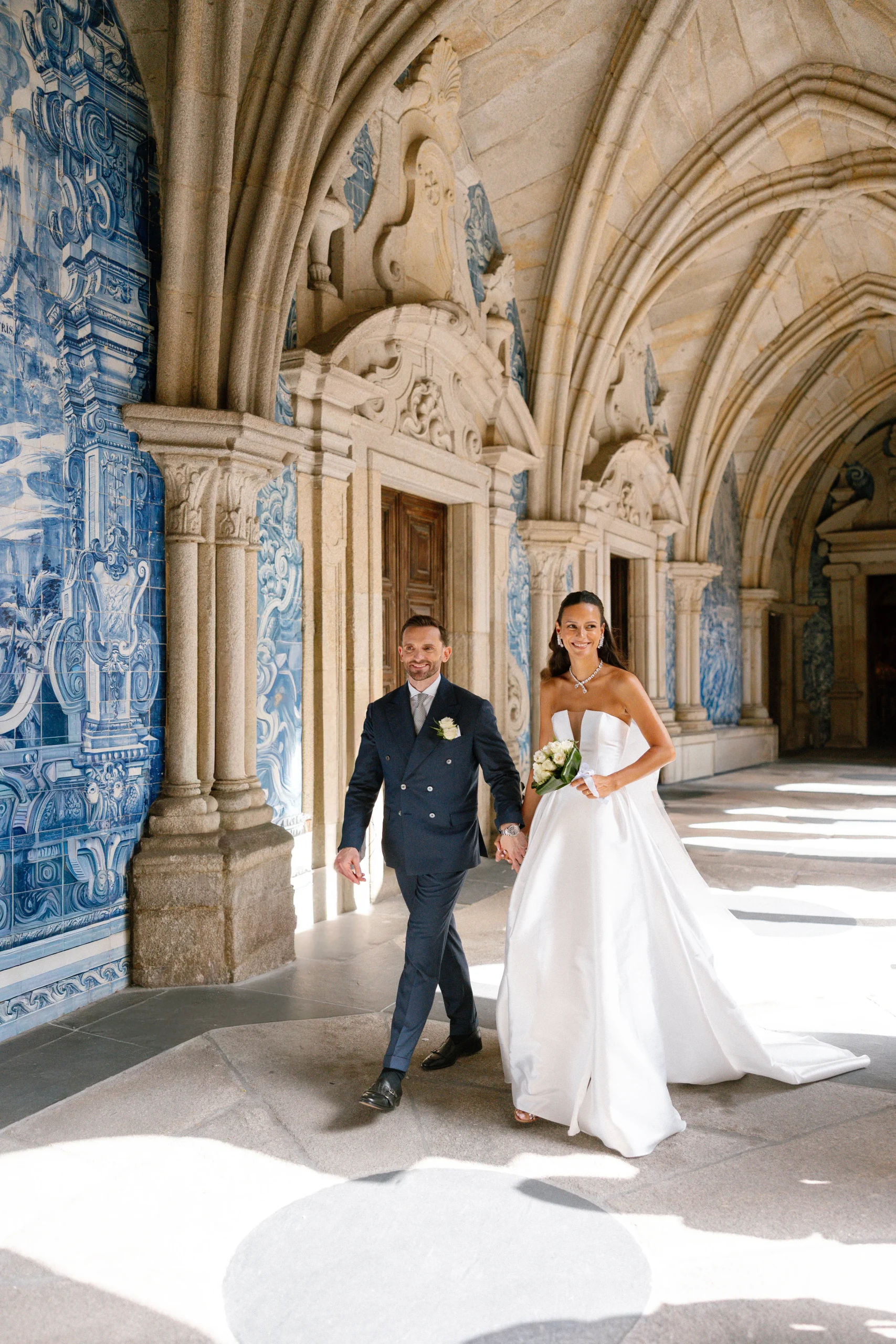 Bride and groom walking through a historic Portuguese venue with blue and white azulejo tiles in Lisbon or Sintra