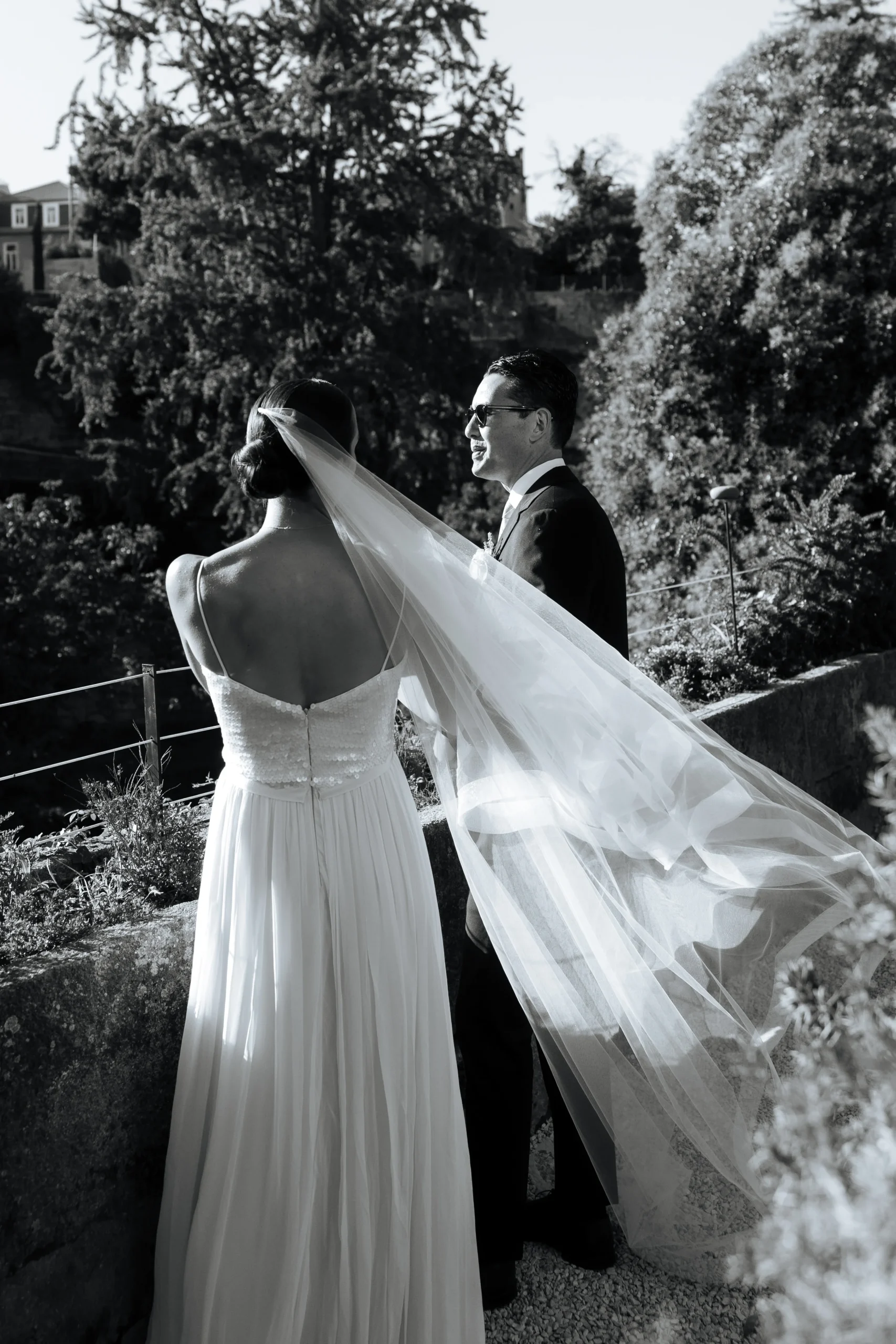 Bride and groom walking together outdoors with the bride´s veil flowing in the wind
